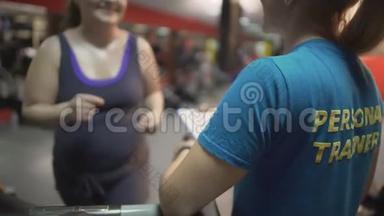 胖女人在健身房和私人教练一起锻炼，在跑步机上锻炼